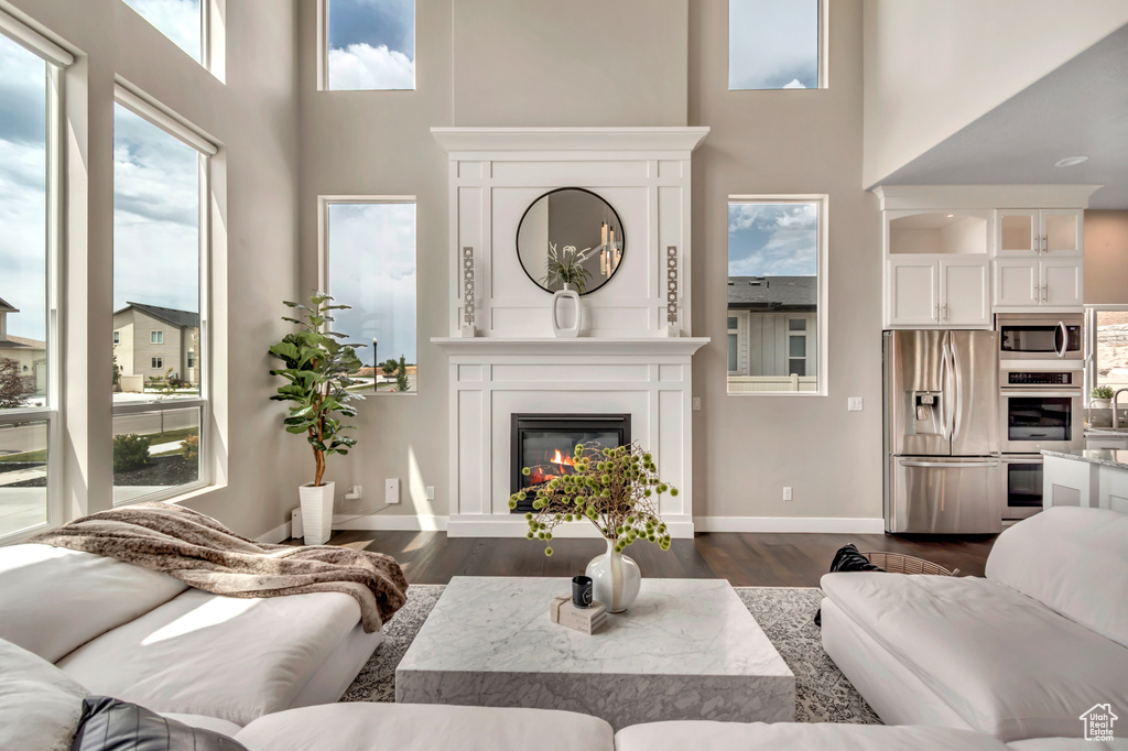 Living area with a towering ceiling, dark wood-style floors, and a glass covered fireplace