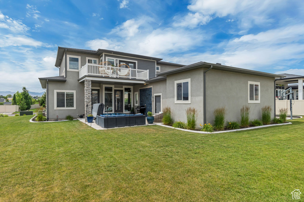 Back of property with stucco siding, a yard, and a balcony