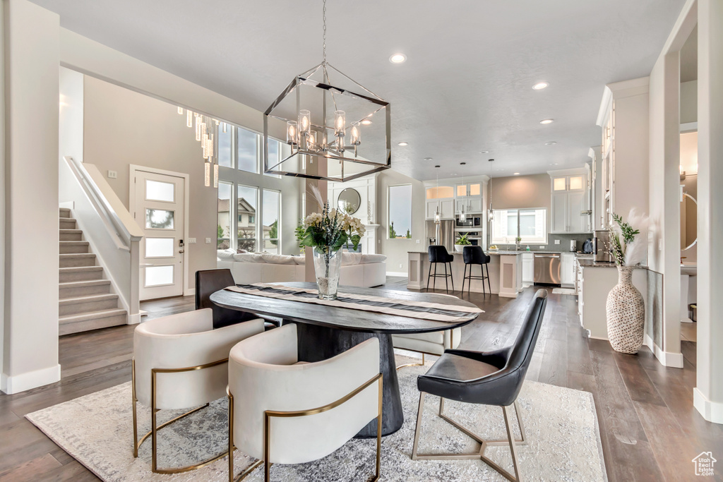 Dining area with stairway, recessed lighting, a chandelier, and dark wood-type flooring