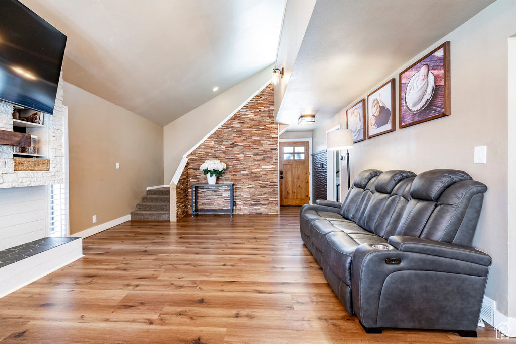 Living area featuring stairway, lofted ceiling, wood finished floors, and a fireplace