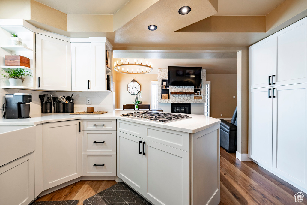 Kitchen featuring open shelves, gas cooktop, wood finished floors, a peninsula, and recessed lighting