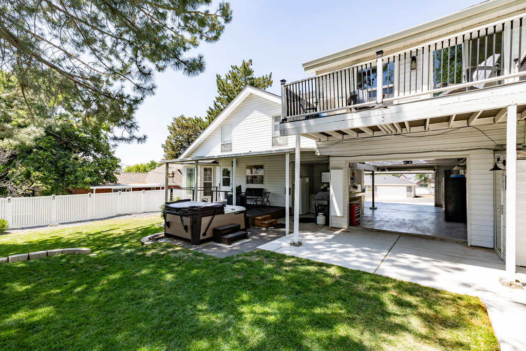Back of property with a hot tub and a patio