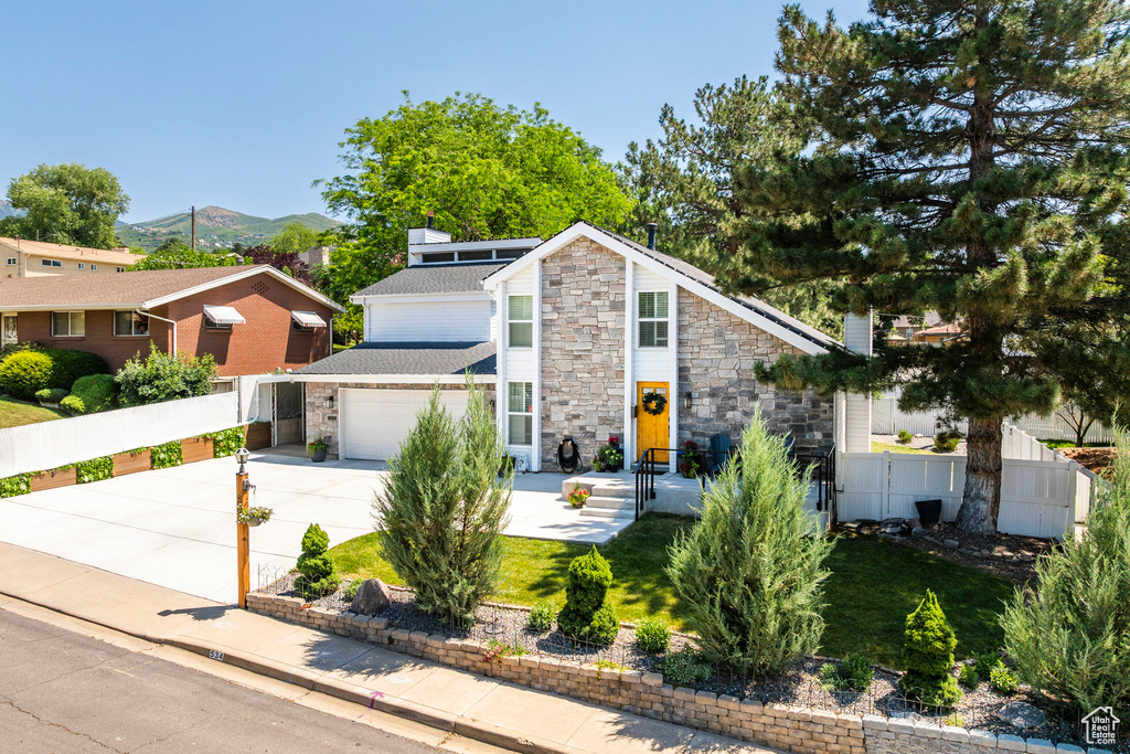 Mid-century inspired home with stone siding, driveway, a mountain view, and a garage