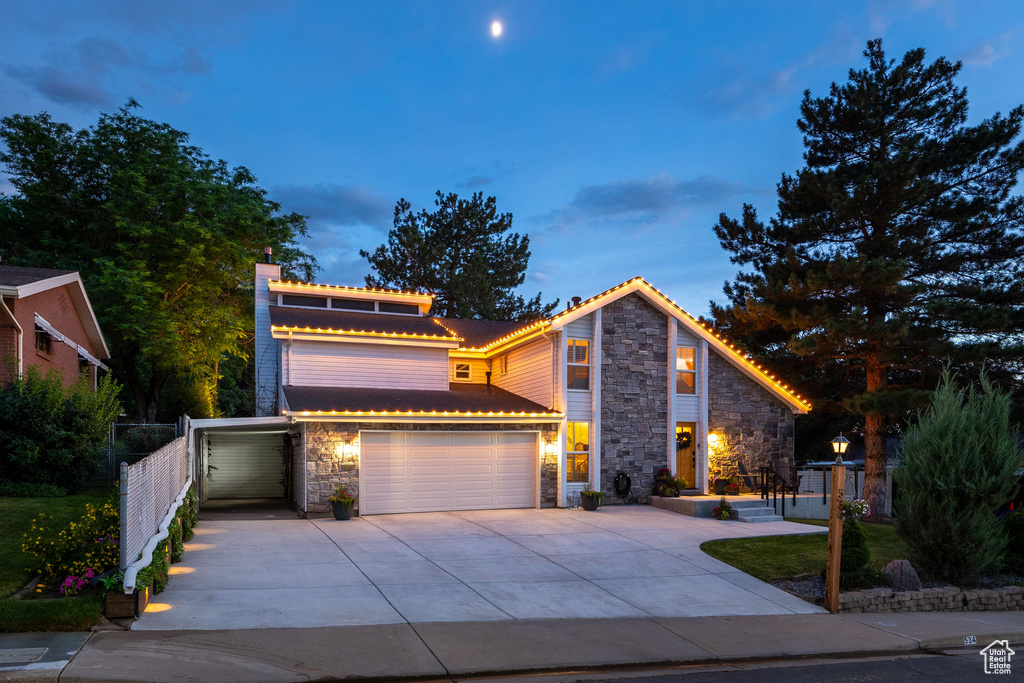View of front of home featuring stone siding, driveway, a chimney, and a garage