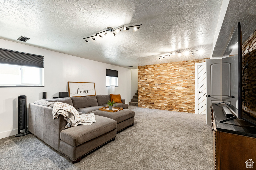 Carpeted living room with rail lighting, a textured ceiling, and stairs