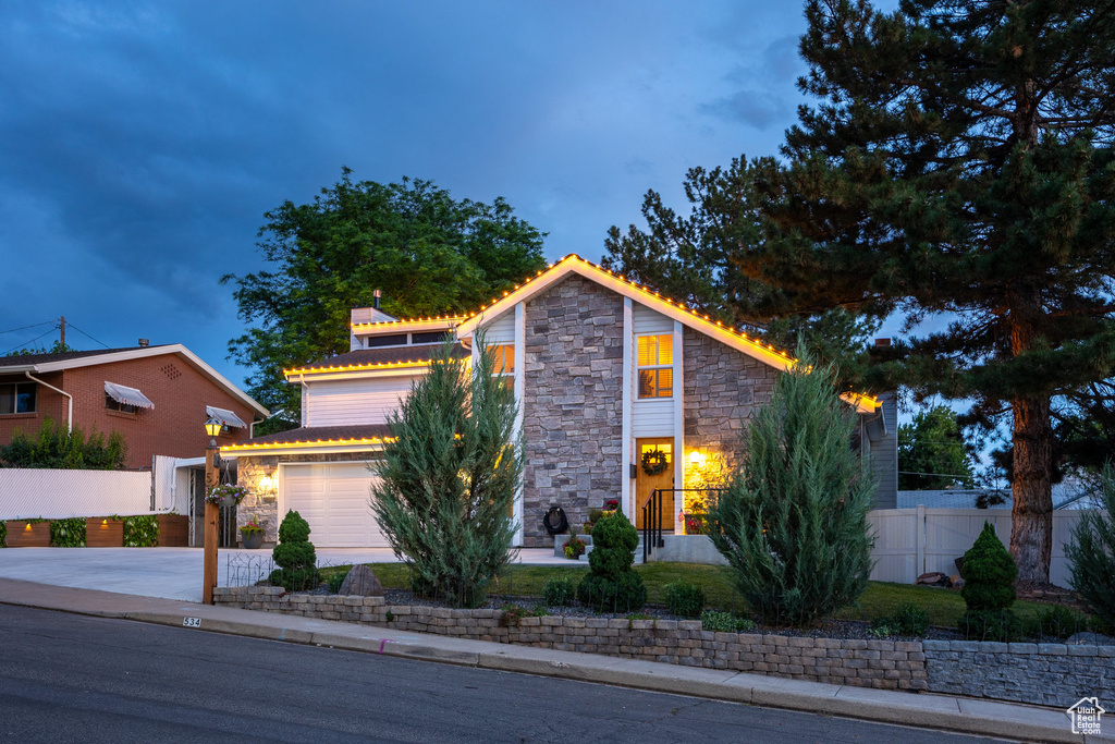 View of front of property with stone siding, concrete driveway, and a garage