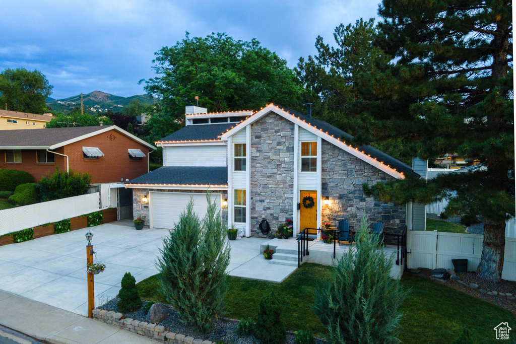 View of front facade featuring stone siding, driveway, an attached garage, and a mountain view