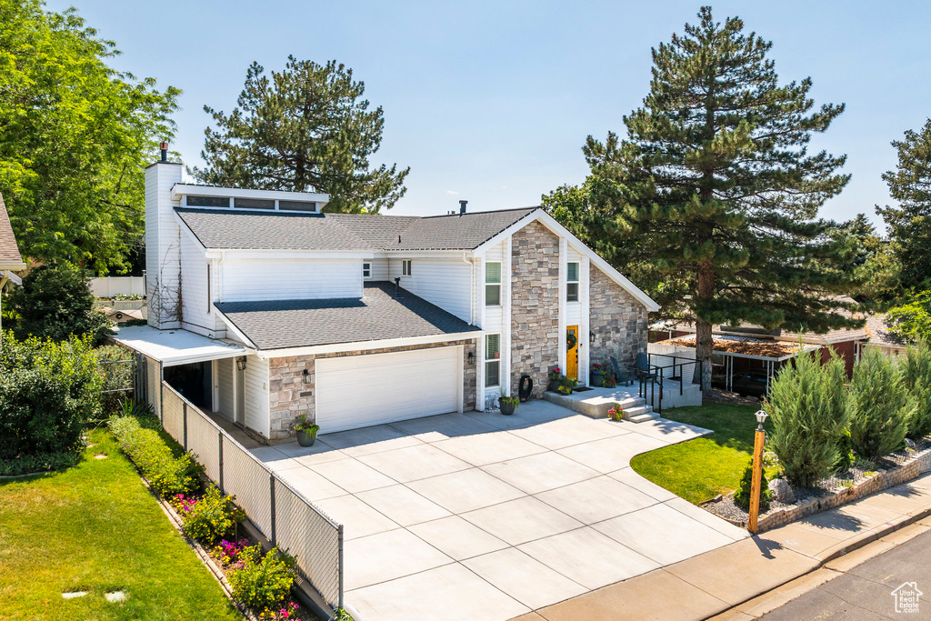View of front of home with stone siding, driveway, a garage, a chimney, and a shingled roof