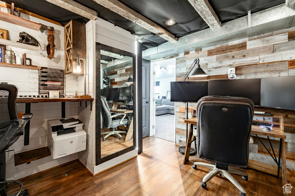 Home office with wooden walls, wood finished floors, and beamed ceiling