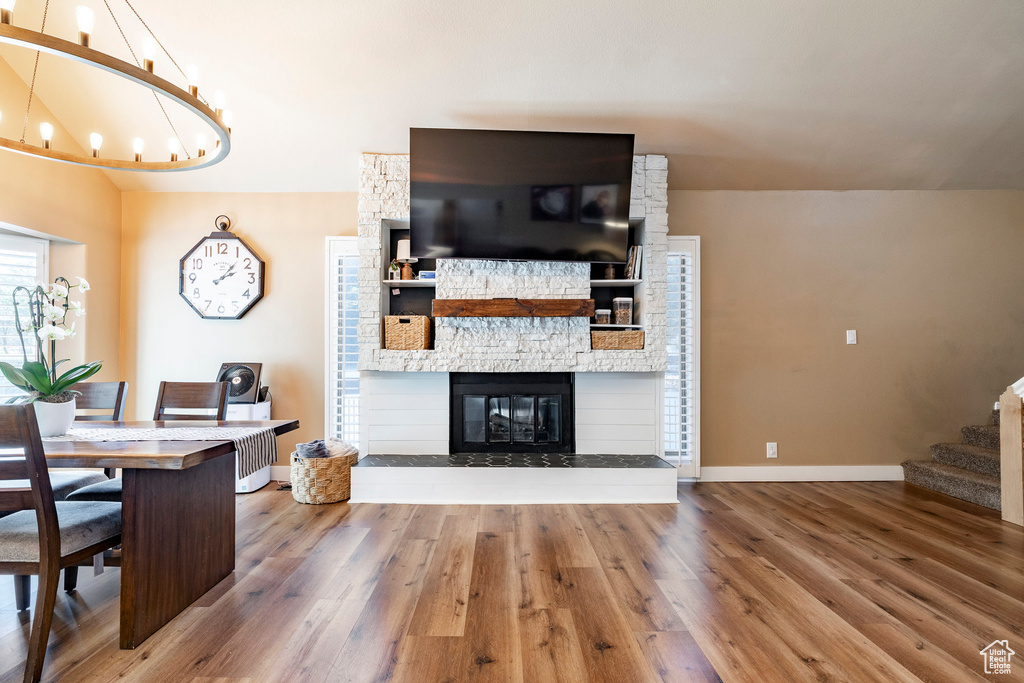Living area featuring wood finished floors, stairs, a fireplace, and a chandelier