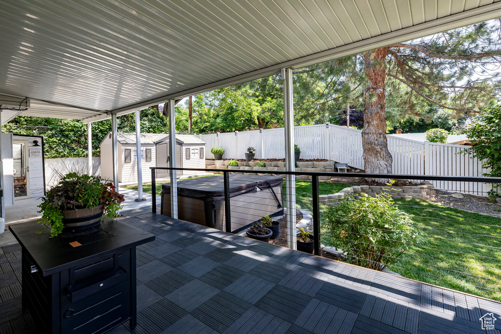 Fenced backyard featuring a storage shed, a hot tub, and a patio