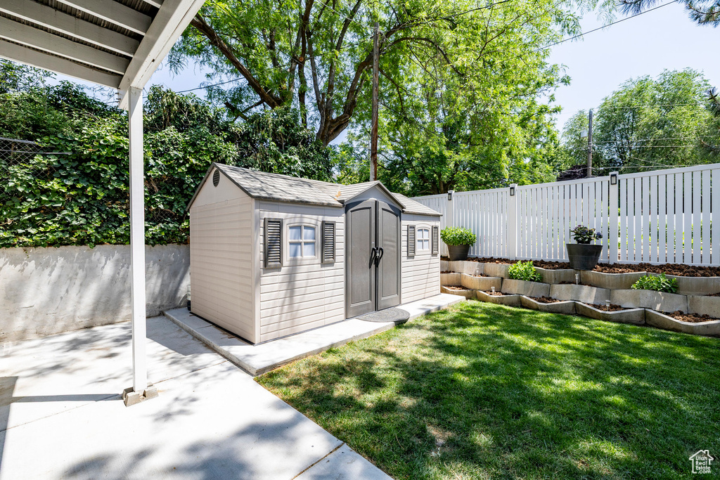 Fenced backyard featuring a storage shed and a patio area