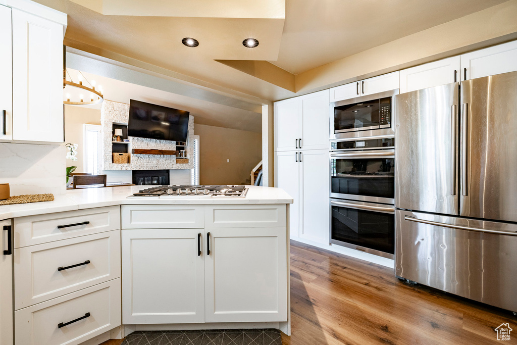 Kitchen featuring appliances with stainless steel finishes, white cabinets, wood finished floors, light countertops, and recessed lighting