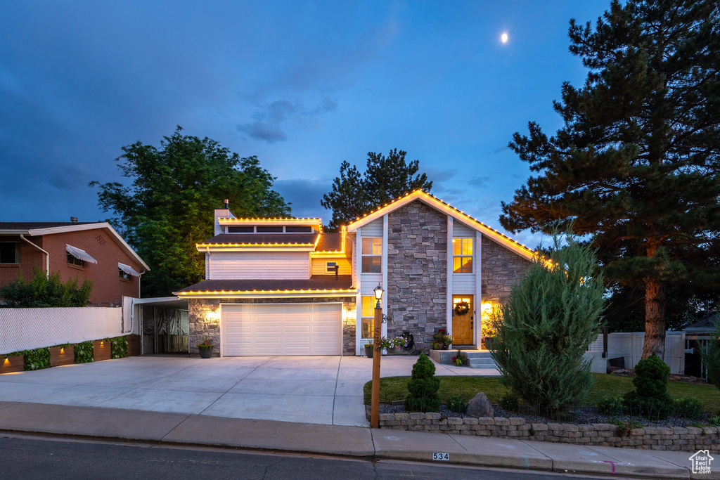 View of front facade featuring stone siding, driveway, and a garage