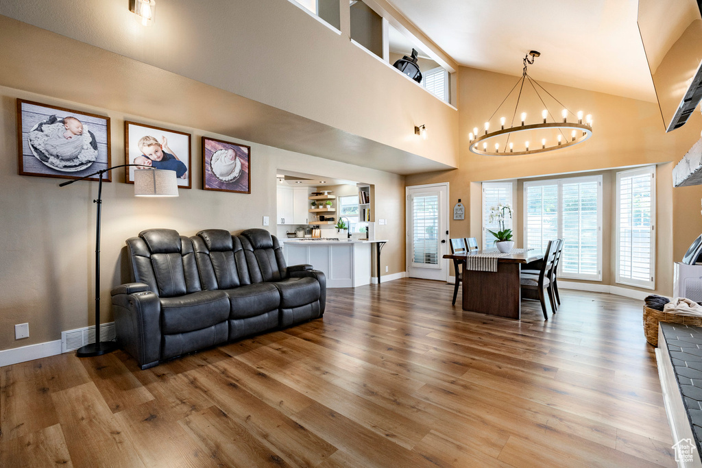Living room with hardwood / wood-style flooring, a chandelier, and high vaulted ceiling
