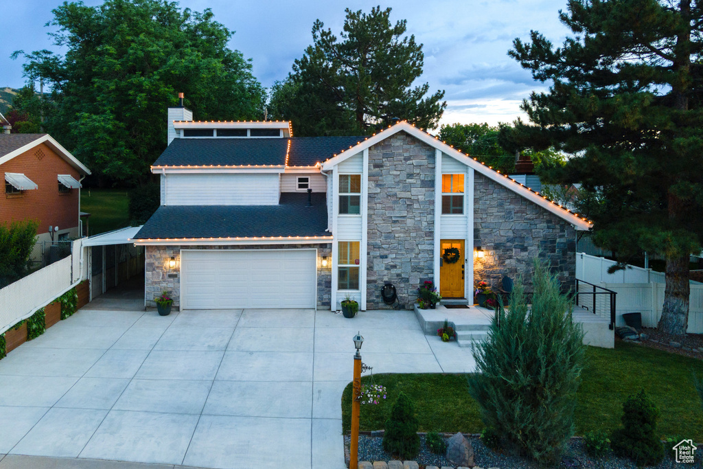 View of front of house with stone siding, driveway, and a carport