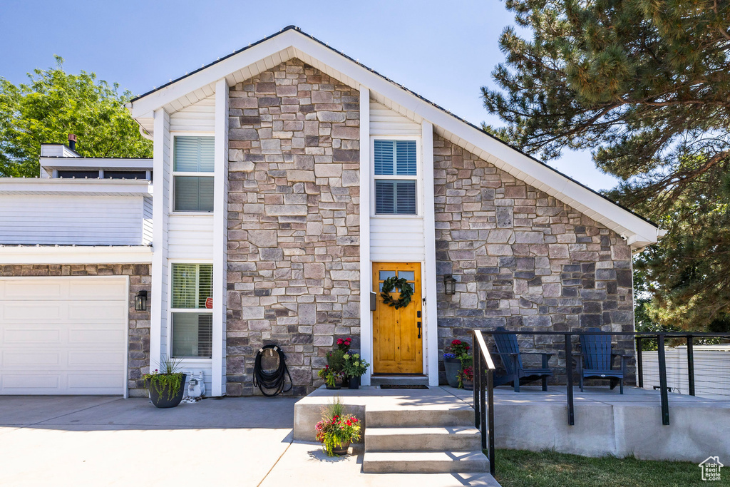 View of front of home with stone siding, a garage, and concrete driveway