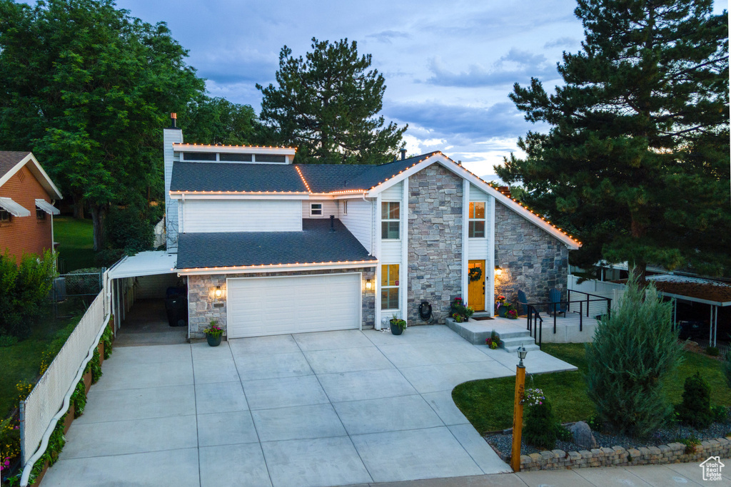 View of front of house featuring stone siding, a chimney, driveway, and a garage