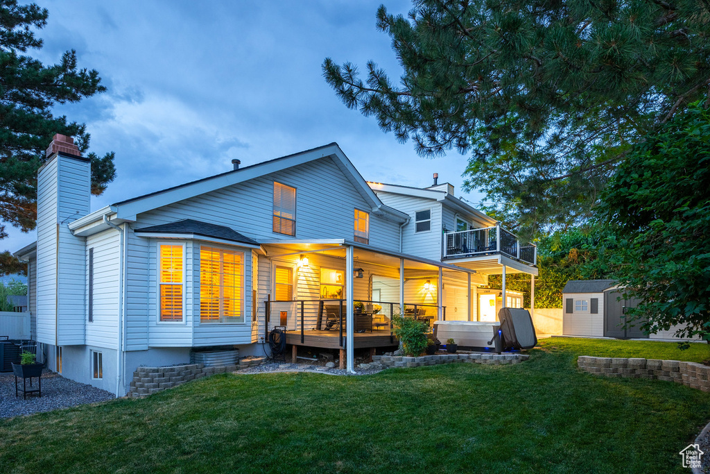 Back of house with a chimney, a storage shed, a yard, a balcony, and a deck