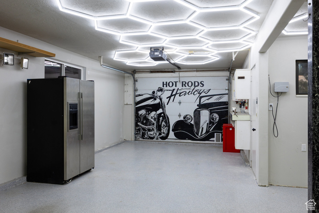 Garage featuring stainless steel fridge and a garage door opener