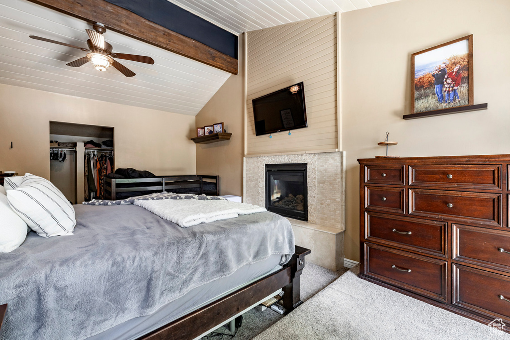 Bedroom with carpet flooring, a glass covered fireplace, a closet, and a ceiling fan