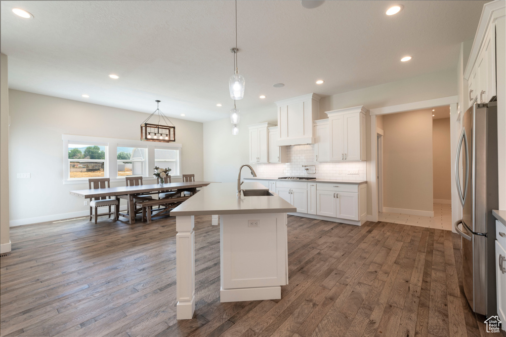 Kitchen featuring freestanding refrigerator, decorative backsplash, wood finished floors, white cabinets, and recessed lighting