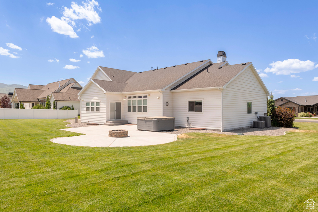 Rear view of property with a patio area, a hot tub, roof with shingles, a chimney, and an outdoor fire pit