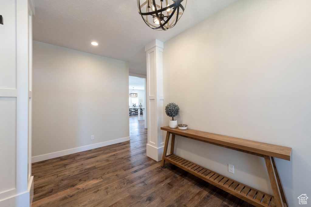 Hallway with dark wood finished floors, recessed lighting, and a chandelier