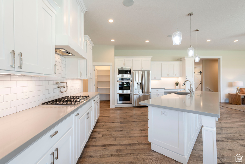 Kitchen featuring appliances with stainless steel finishes, dark wood-style flooring, recessed lighting, decorative backsplash, and white cabinets