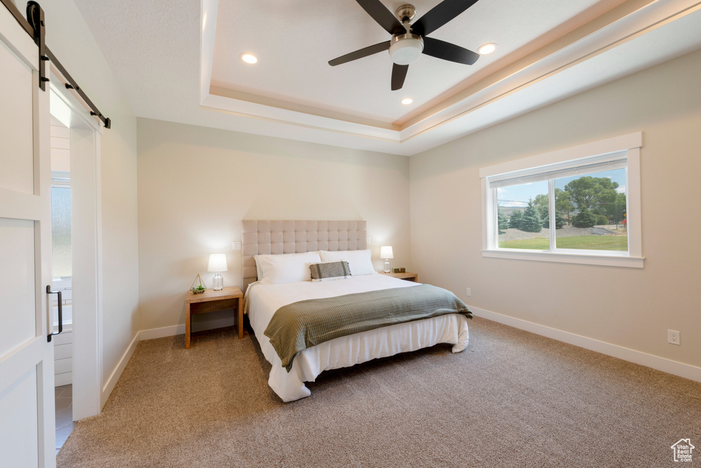 Bedroom with a barn door, a tray ceiling, carpet, recessed lighting, and ceiling fan