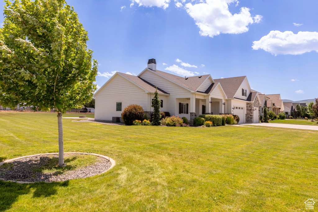 View of front of home with concrete driveway, a chimney, a front lawn, an attached garage, and a shingled roof