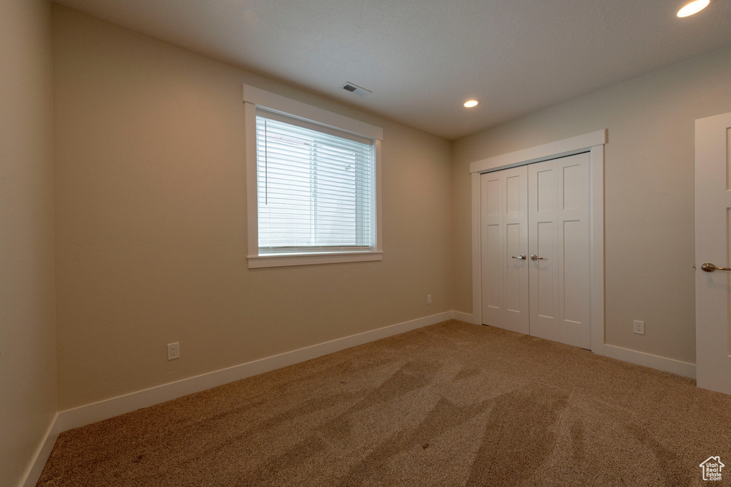 Unfurnished bedroom featuring recessed lighting, light carpet, and a closet