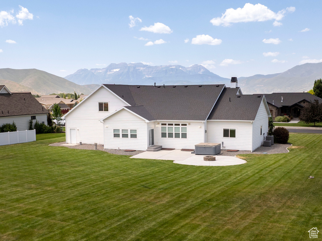 Back of house featuring a patio, a mountain view, a hot tub, and a chimney