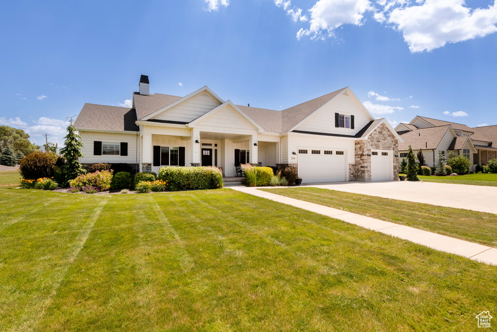 View of front of property featuring driveway, a chimney, a garage, and a front yard