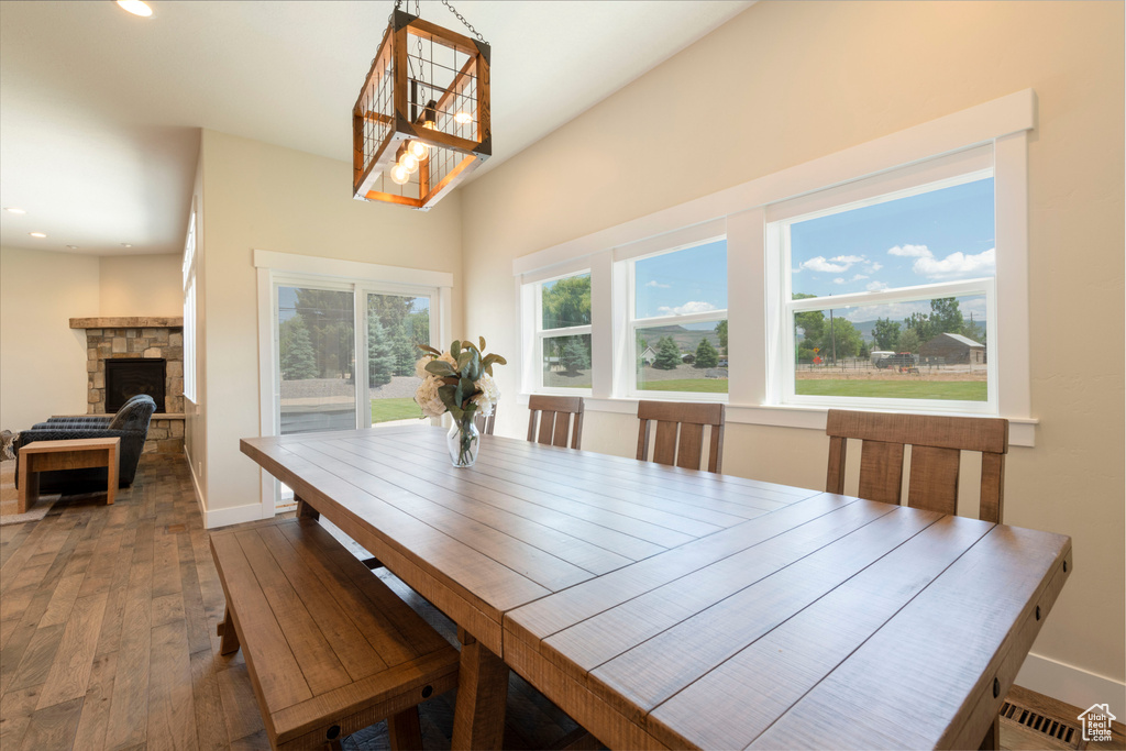 Dining area with hardwood / wood-style floors, recessed lighting, and a stone fireplace