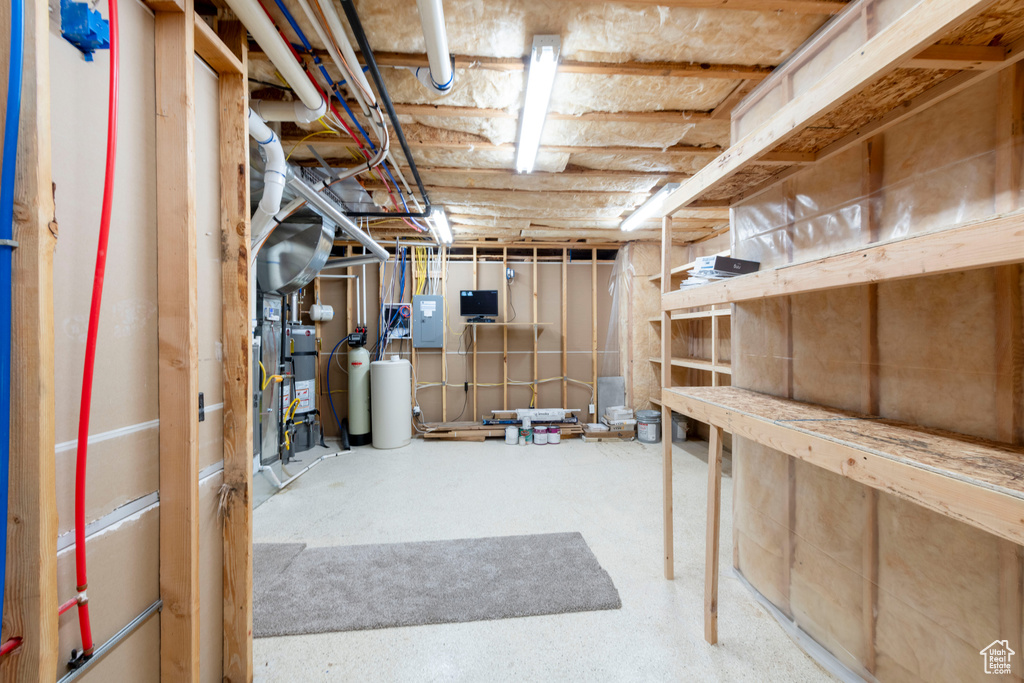 Unfinished below grade area with electric panel, a water softener, and water heater