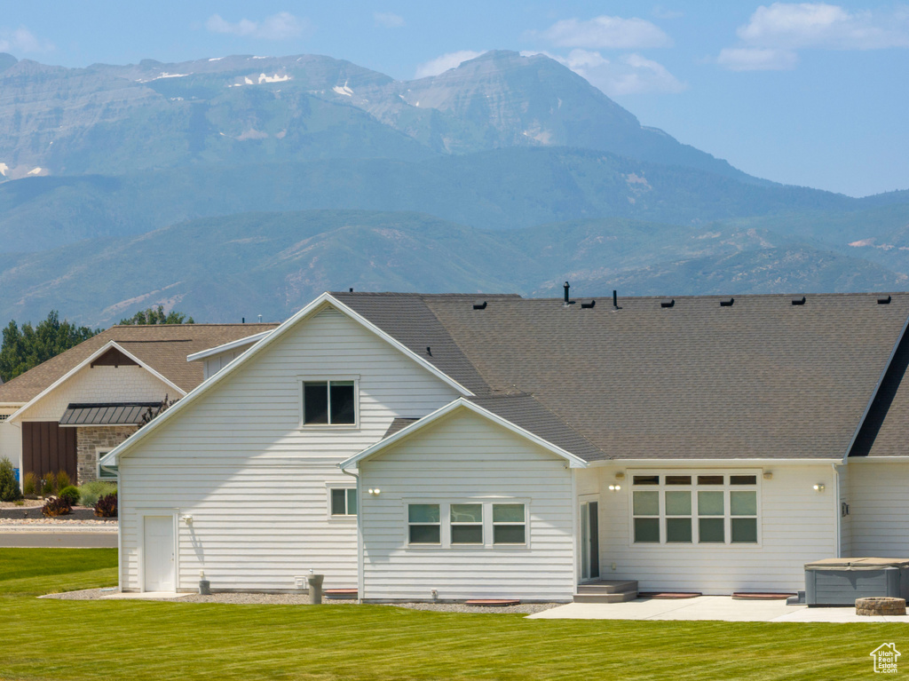 Rear view of house with a mountain view, a yard, and a hot tub
