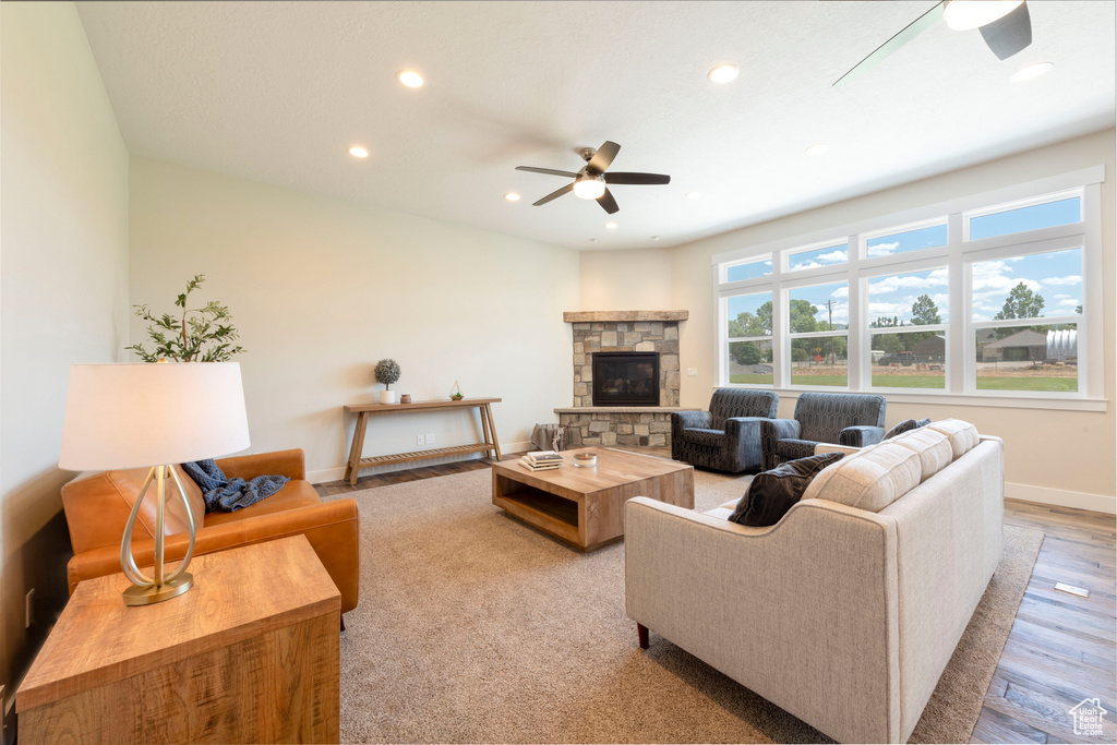 Living area featuring a ceiling fan, recessed lighting, a fireplace, and wood finished floors