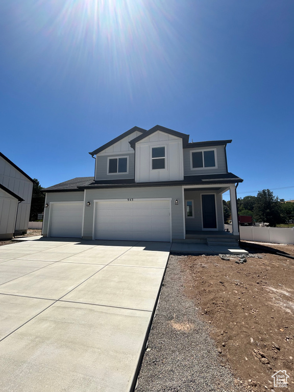View of front of home with driveway, a garage, and covered porch
