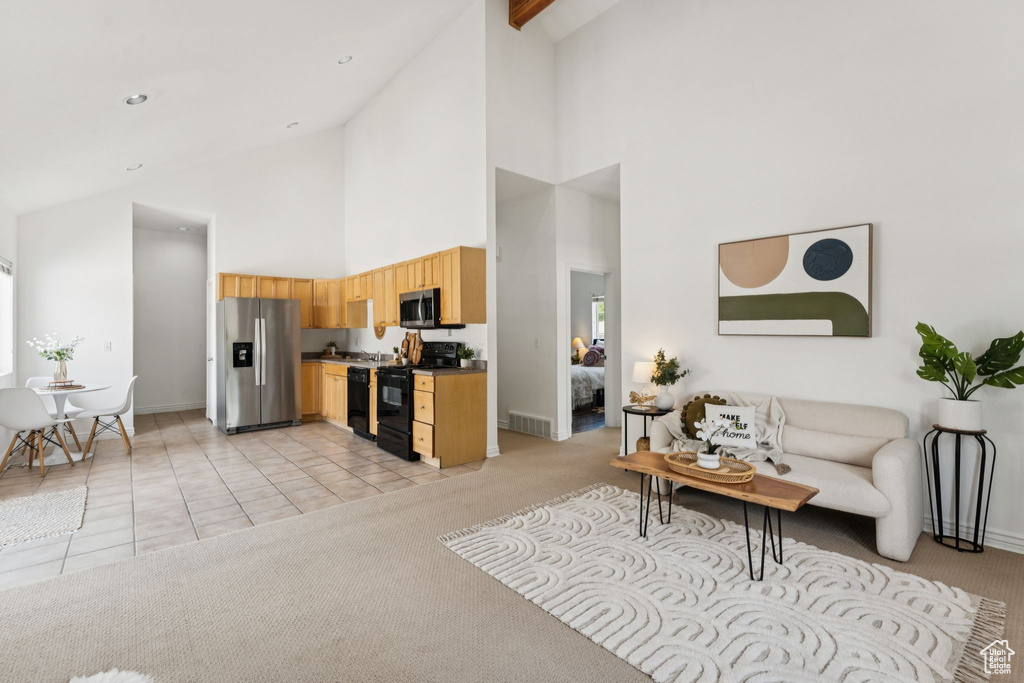 Living room with high vaulted ceiling, light carpet, and light tile patterned floors