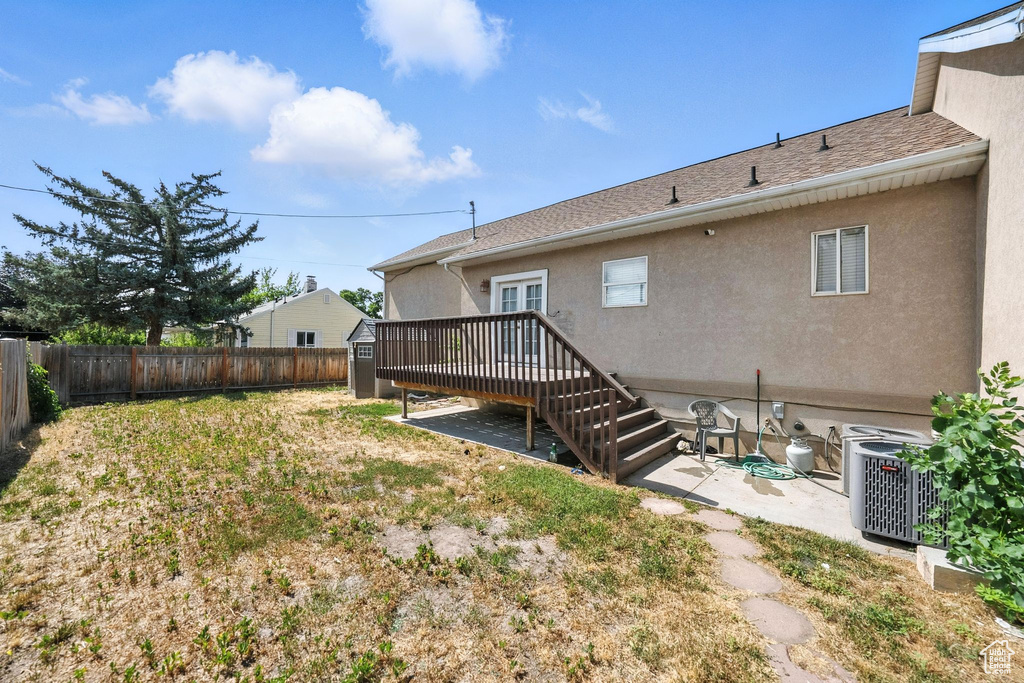 Back of property featuring a fenced backyard, a storage shed, a patio, stucco siding, and a deck