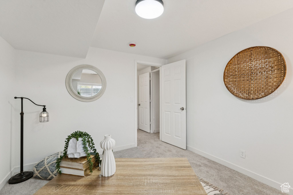 Hallway with light colored carpet and baseboards