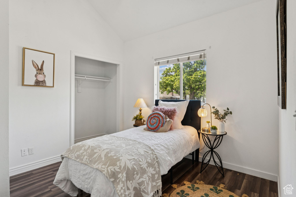 Bedroom featuring dark wood-style flooring, a closet, and high vaulted ceiling
