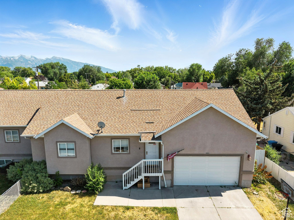 Ranch-style house with concrete driveway, stucco siding, a garage, a mountain view, and roof with shingles