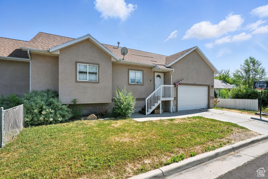 View of front of home with driveway, stucco siding, an attached garage, and roof with shingles