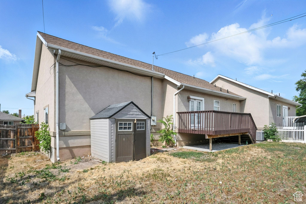 Back of house featuring a deck, a shed, and stucco siding