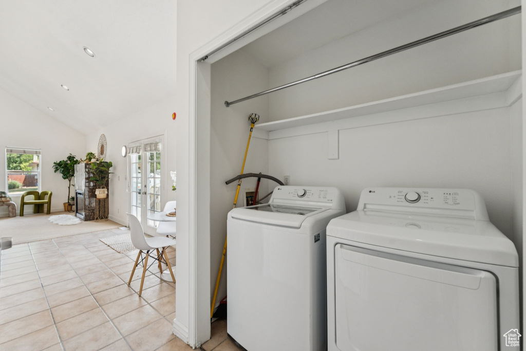 Laundry area featuring washer and dryer, light tile patterned floors, and french doors