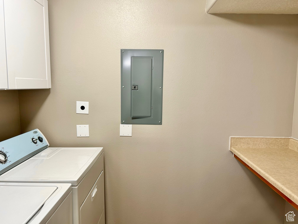 Laundry area featuring electric panel, cabinet space, and washing machine and dryer