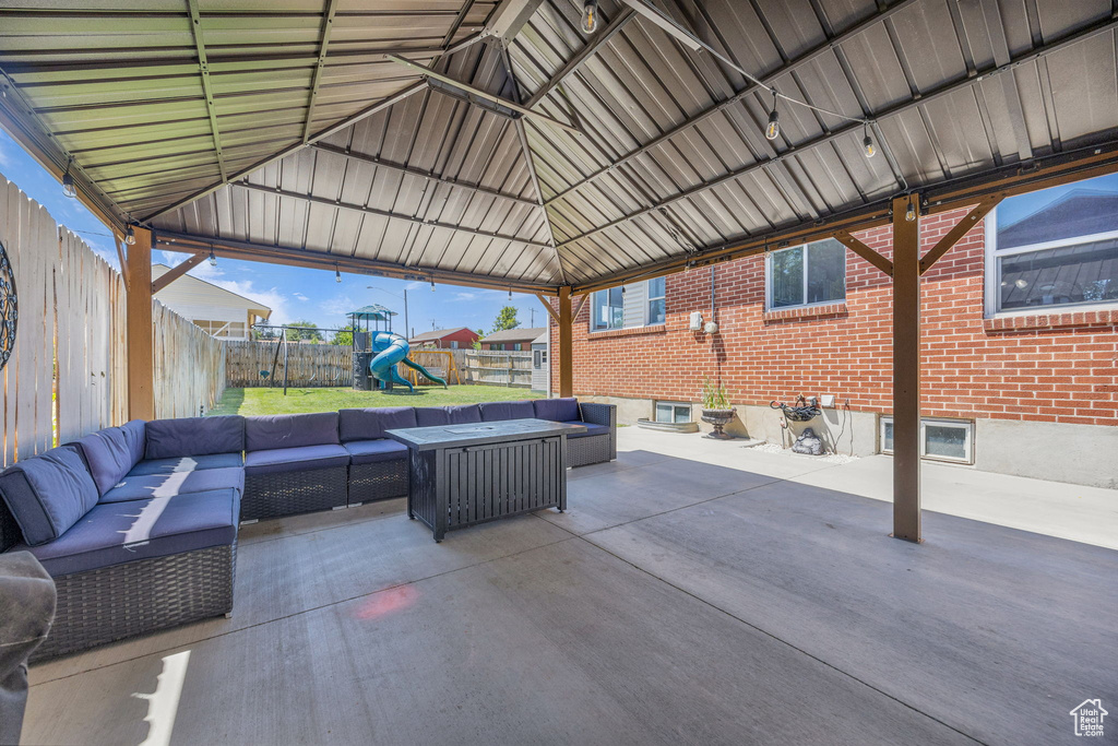 Fenced backyard featuring an outdoor living space, a playground, and a patio