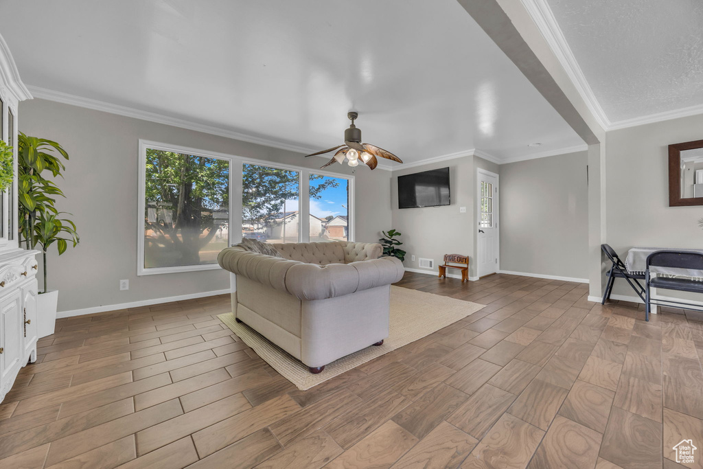 Living area with ceiling fan, ornamental molding, and wood finished floors
